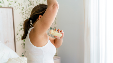 A woman putting on deodorant.