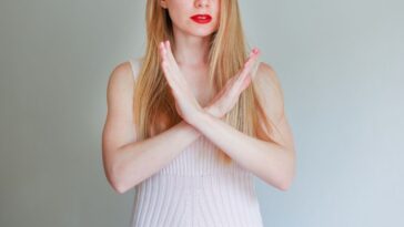 Photo of a pretty woman with her hands crossed as to show a 'no stop, forbidden' symbol on an isolated background.