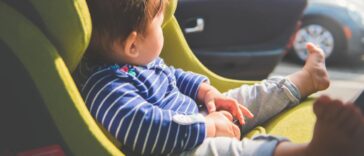 A baby girl 8 months old sitting in her car seat enjoying the warmth of the sun.