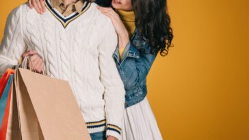 Cropped image of couple with shopping bags isolated on yellow background.