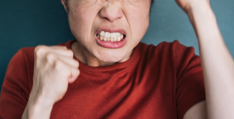 A woman with a clenched jaw holding her fists in the air.