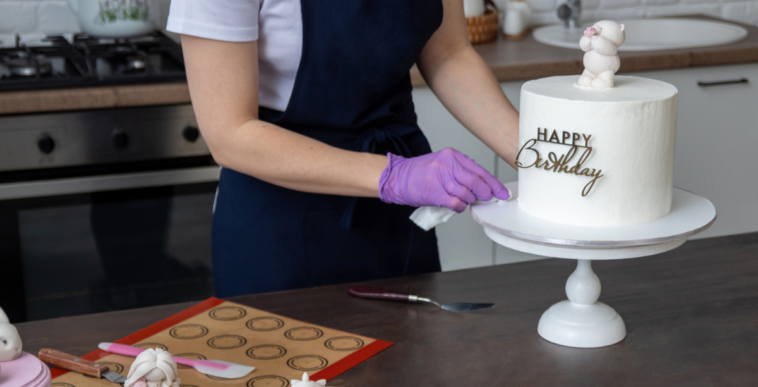A woman decorating a cake with the words "Happy Birthday" on it.