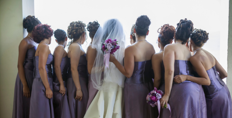 A bride surrounded by Bridesmaids in purple dresses.