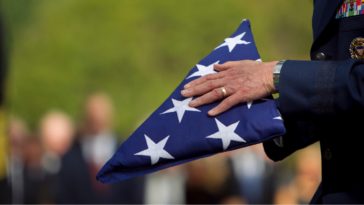 A man in a military uniform holding a folded American flag.