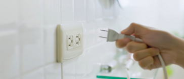 A hand unplugging a plug from a socket.