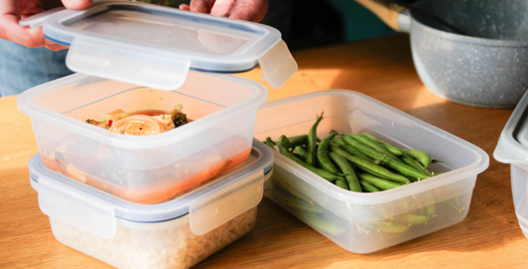 Someone assembling tupperware containers full of leftovers.