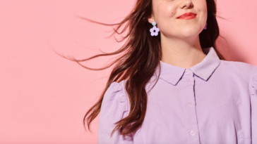 A woman standing in front of a pink wall.