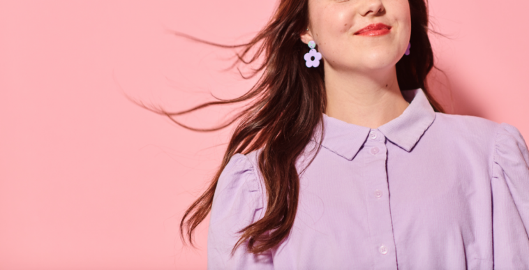 A woman standing in front of a pink wall.