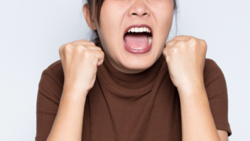 A woman clenching her fists and screaming.
