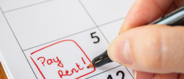 Someone writing "pay rent" on a calendar.
