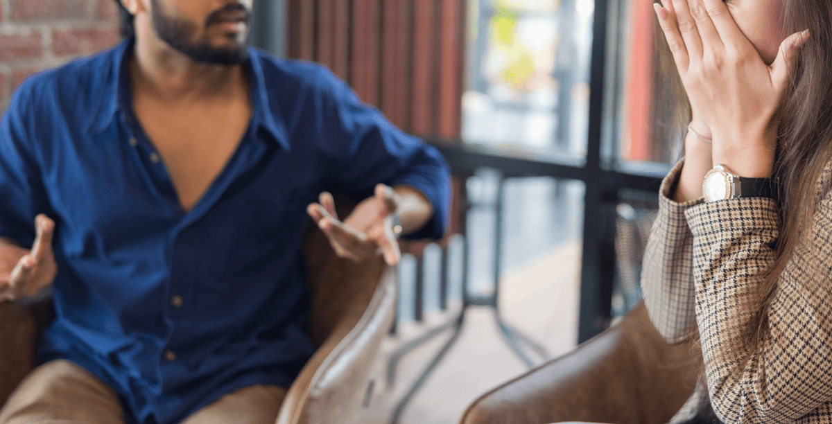 A woman covering her fave sitting next to a man making emmphatic gestures.