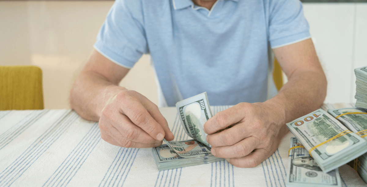 A man sitting at a table counting money.