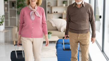An older couple pulling rolling luggage.
