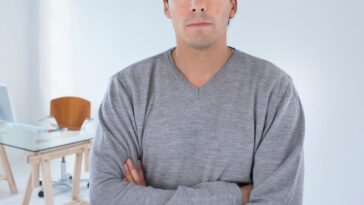 Man standing in an office arms crossed.