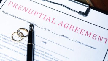 Close-up of a prenuptial agreement form with wedding rings and a fountain pen, indicating the legal aspects of marriage preparation.