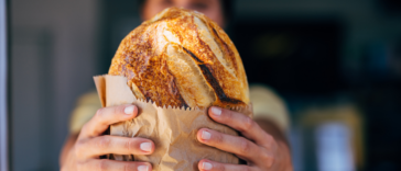 woman holding bread wrapped in brown paper