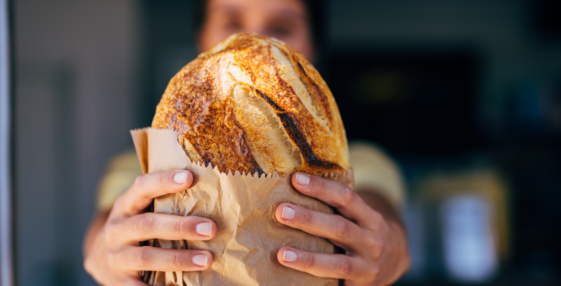 woman holding bread wrapped in brown paper