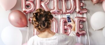 woman in white takes selfie in front of bridal shower decorations