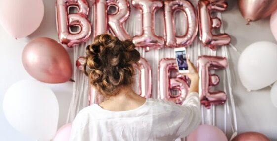 woman in white takes selfie in front of bridal shower decorations